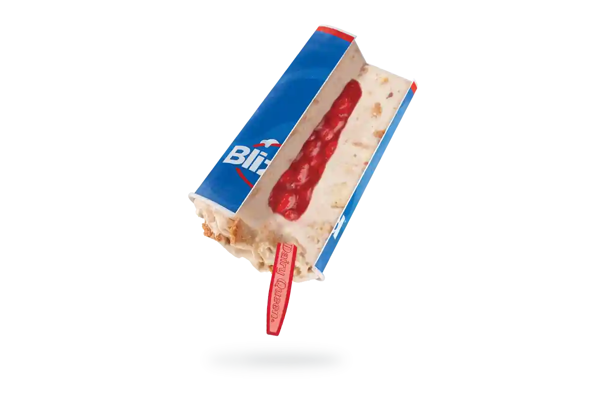 Upside down Royal New York Cheesecake Blizzard with a red spoon is cut open to show the core filled with strawberry topping.